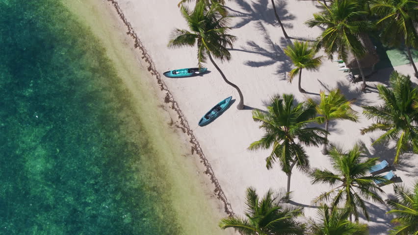 Stunning aerial view of Sunset Key in Key West, showcasing pristine beaches, green palm trees, and turquoise waters under bright sunshine