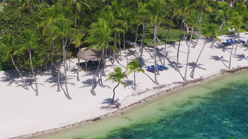 Experience the stunning aerial view of Sunset Key with its pristine sandy beaches, lush palm trees, and vibrant turquoise waters, showcasing the unique charm of Key West