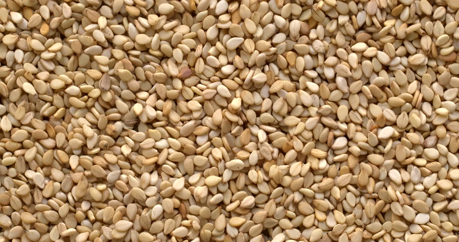 Unhulled sesame seeds background texture, close-up. A common ingredient in cuisines worldwide, with one of the highest oil contents of any seed. Table spin.