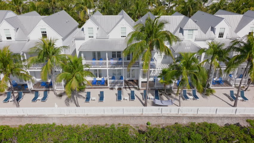 An aerial view showcases Sunset Key in Key West, Florida, highlighting its vibrant palm trees, sandy beaches, and luxurious beachfront properties that attract tourists worldwide