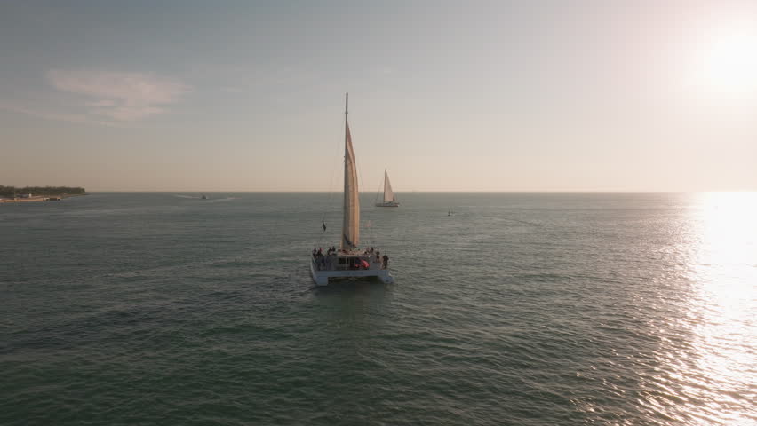 An aerial view highlights a sailboat gliding over clear waters near Sunset Key, Key West, Florida, capturing the essence of tropical adventures and unforgettable summer getaways