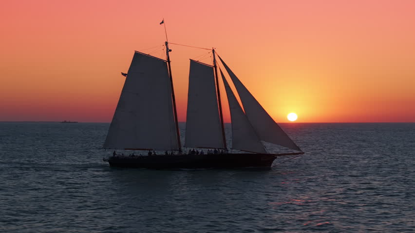 This aerial view shows a stunning sunset sailboat in Key West, Florida, with vibrant colors and serene waters, perfect for relaxation