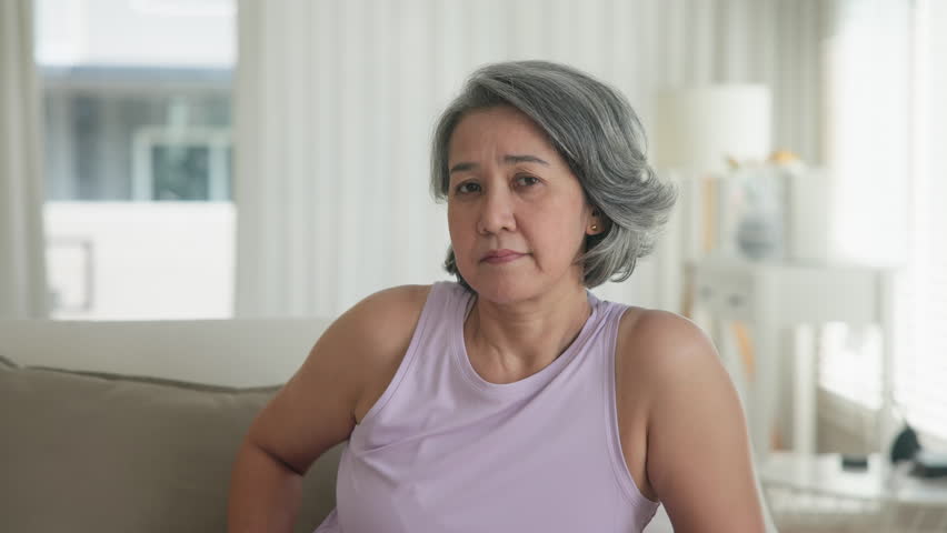 Asia adult boring people middle age old woman sit angry at sofa home anger hot flash elder mental health care aging issue. Aged stress bored toxic pain sad upset face. Female asian burnout support.