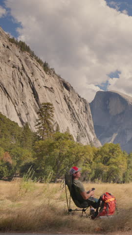 A man enjoys a welldeserved break from his busy life to appreciate the breathtaking beauty of Yosemite National Park, relaxing in a chair amid the stunning natural landscape and serene atmosphere