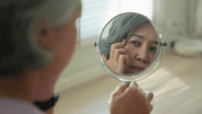 Asia adult people middle age old woman look at mirror dry skin face hand touch neck cheek stress sad at home elder health care aging beauty issue. Asian female aged eye botox filler plastic surgery. - Powered by Shutterstock - Get 15% off with code: PIKWIZARD15