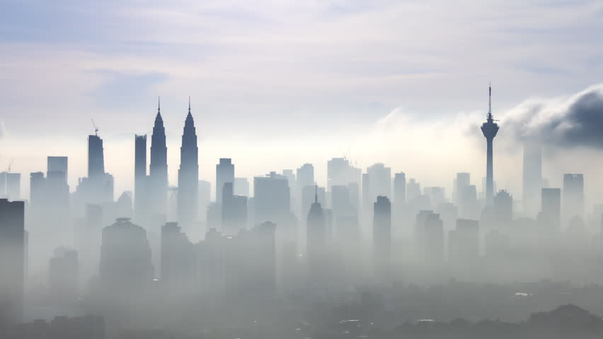 Time lapse: Silhouette of KL cityscape view during misty morning overlooking the city skyline from afar with yolk sun and lushes green in the foreground. Kuala Lumpur, Malaysia. Prores 4KUHD available