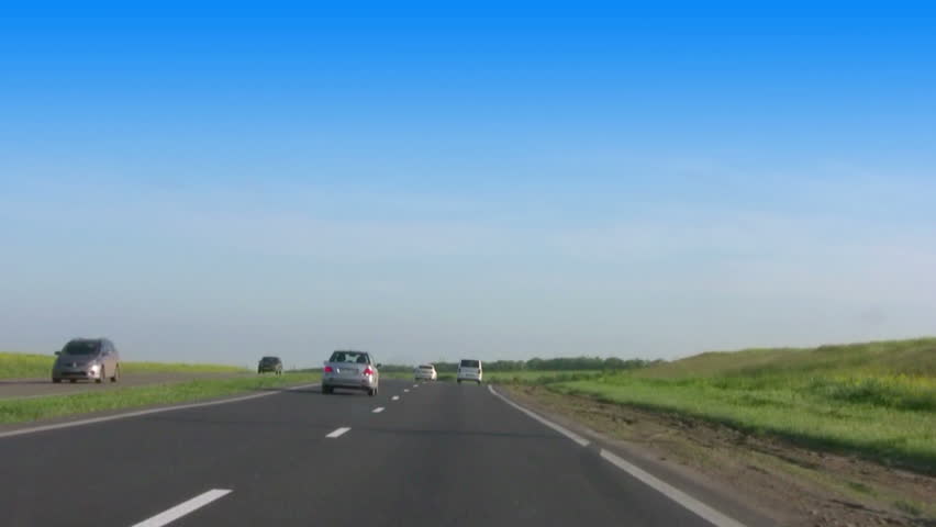 Sunny day. The viewer moves the car along the highway in the steppe