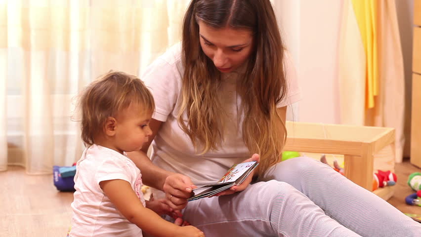 Education: mother reading book to small girl at home