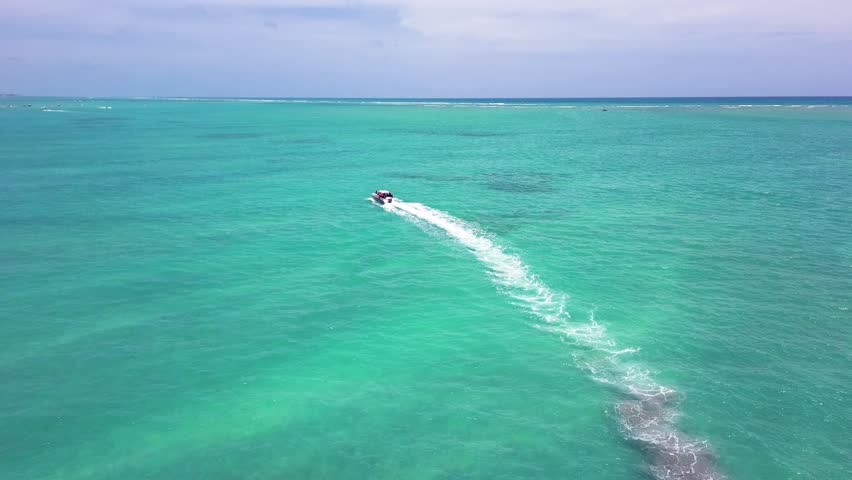 An animation of a sleek boat cruising along the clear waters of Dubai’s coastline, with iconic landmarks like the Burj Al Arab in the background, and the golden sunset reflecting on the water.