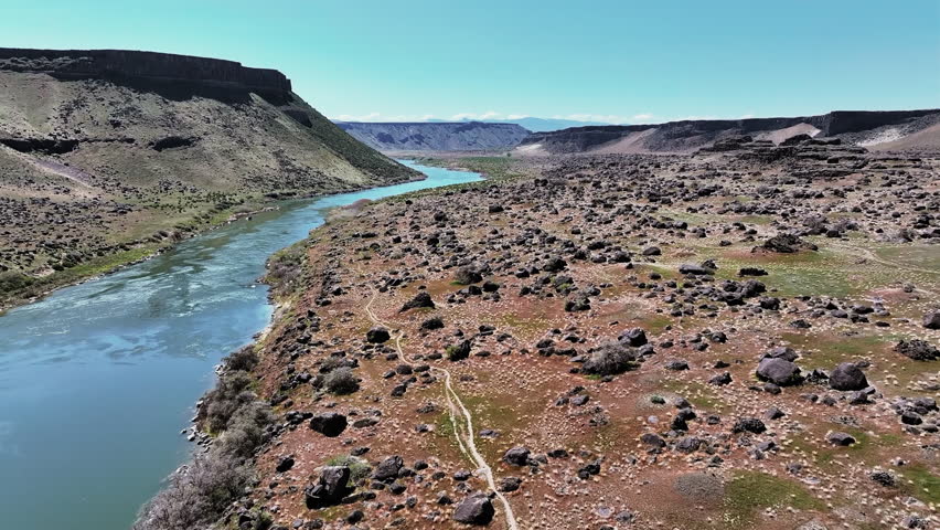 Aerial view of Snake River Canyon in Idaho, featuring dramatic cliffs, a winding river, and stunning desert landscapes. Wide view