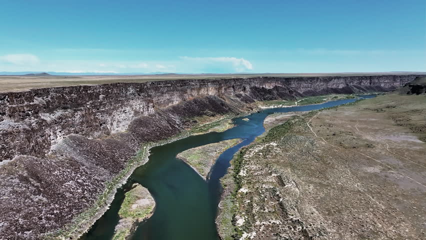 Aerial view of Snake River Canyon in Idaho, featuring dramatic cliffs, a winding river, and stunning desert landscapes.