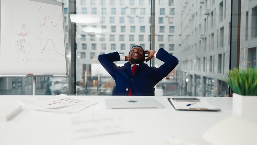 Happy boss in his office, African American man relaxing on chair and smiling. Office worker enjoying new office room and successful career in corporation, good mood and positivity, black male person