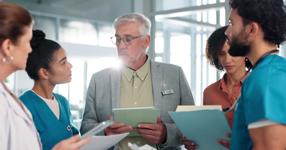 Doctors, man and team with documents in hallway with leader, report and tablet for medical solution. People, listen and discussion with group, paperwork and planning strategy for surgery at hospital