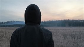 Mystical, creepy, exciting story. A lonely guy with black clothes looks at the fog. Back view. Young lonely guy looking at sunset. Mystical view, fog over the field during sunset. - Powered by Shutterstock - Get 15% off with code: PIKWIZARD15