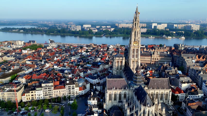 Summer Morning in Antwerp: A High-Angle Aerial View of the City, Centered on the Majestic Cathedral of Our Lady with Its Towering Spire, Overlooking the River Scheldt and the City's Historic Buildings