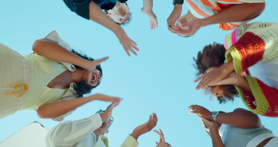 Happy people, hands together and huddle with applause for motivation below for unity, teamwork or mission. Low angle, group or circle with piling or stack in solidarity for community development