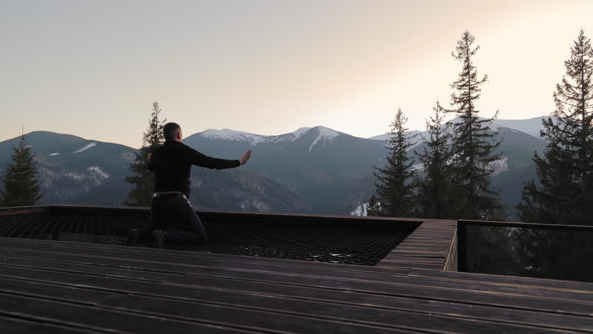Man meditating in the mountains, peaceful winter scenery with trees and snowy peaks
