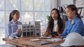 Three female engineers are having a meeting in the office, discussing a sustainable factory project using a wind turbine, analyzing blueprints and calculating costs - Powered by Shutterstock - Get 15% off with code: PIKWIZARD15