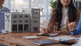 Professional architects analyzing a building model, pointing out key features and discussing design elements during a collaborative meeting - Powered by Shutterstock - Get 15% off with code: PIKWIZARD15