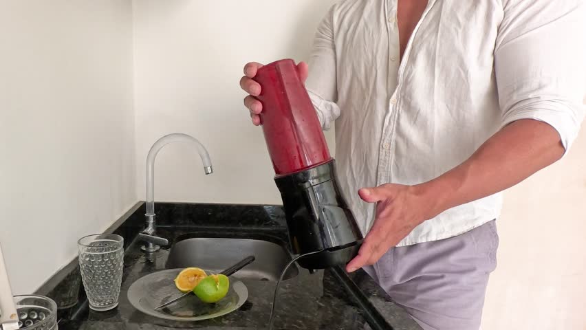Man alone preparing healthy juice from beetroot, orange, spinach