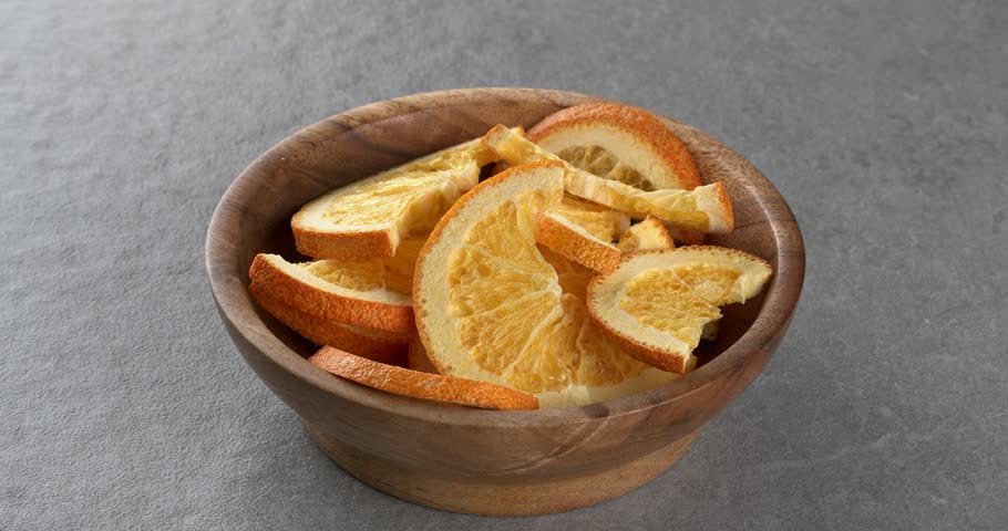 Freeze-dried oranges in wooden bowl. Close-up footage on the rotating table.
