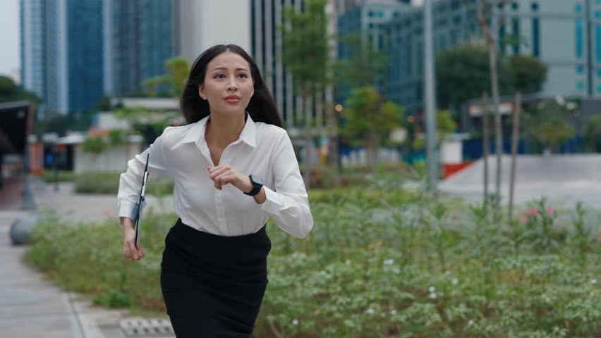 Young Asian Business Lady Running On The Street During Rush Hour. Charming Manager Girl Hurry Up For The Meeting, Looking At The Hand Clock. People Concept