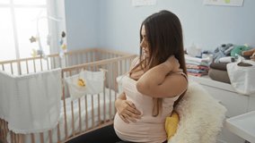 Pregnant woman sits in a cozy baby room, cradling her neck in discomfort with a cradle nearby, embodying maternal anticipation and the reality of pregnancy discomfort. - Powered by Shutterstock - Get 15% off with code: PIKWIZARD15