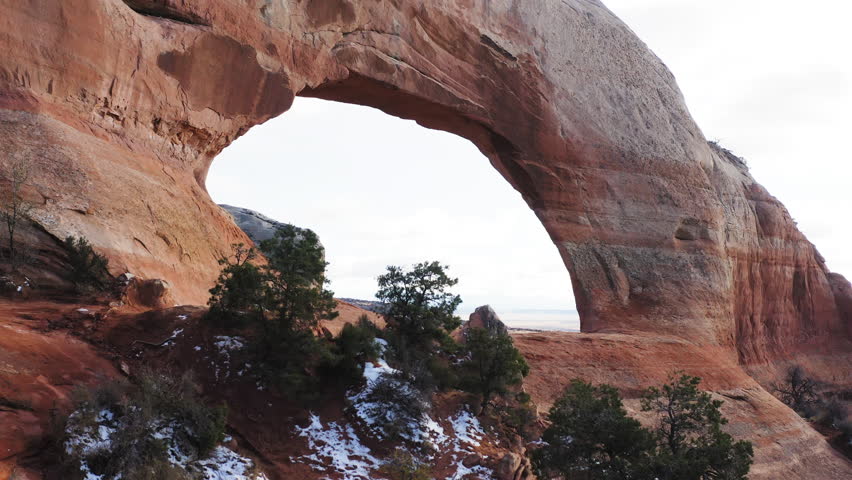 Stunning aerial shot of Wilson Arch, natural sandstone formation, surrounded by rugged desert scenery. Moab, Utah, USA.
