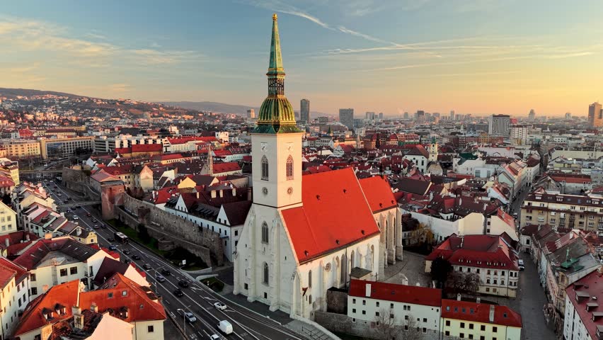 Aerial view of the skyline featuring historic architecture and vibrant rooftops at sunset in Bratislava, Slovakia. Fly around St. Martin