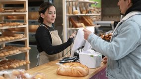 Friendly baker processing digital contactless payment, facilitating smooth transaction with customer at bakery point of sale counter, showcasing modern retail service - Powered by Shutterstock - Get 15% off with code: PIKWIZARD15