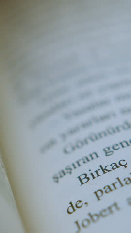 Flipping through the pages of a book, reading literature, close-up shot of printed text in motion ,vertical video