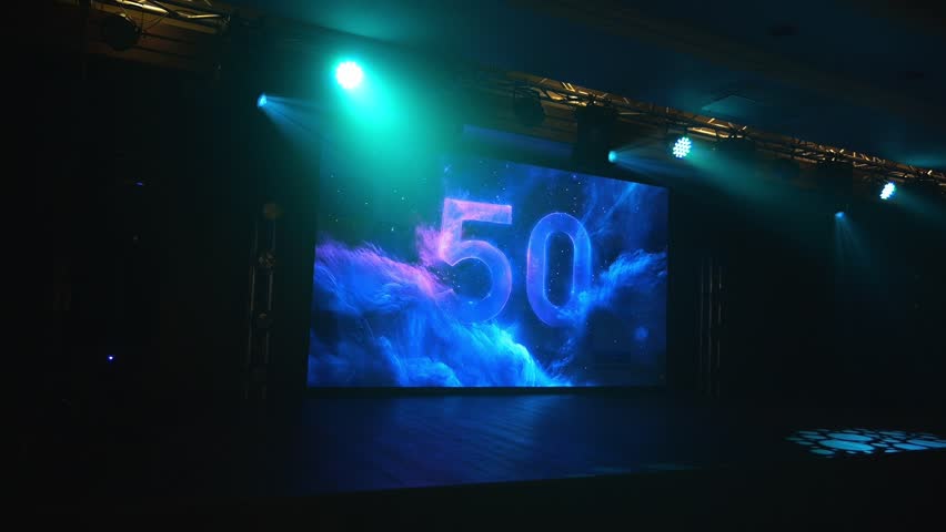 An empty concert stage with a large screen with the number 50, multicolored spotlights flashing with different lights. A festive backdrop for the fiftieth anniversary.