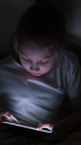 A little girl is playing mobile games on her phone. Addiction to online video games on a smartphone. The concept of children's dependence on technology.