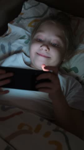 A little girl is playing mobile games on her phone. Addiction to online video games on a smartphone. The concept of children's dependence on technology.