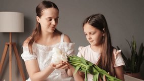 A mother presents a bouquet of white flowers to her daughter in a warm and inviting indoor space. The atmosphere radiates love and joy between them - Powered by Shutterstock - Get 15% off with code: PIKWIZARD15