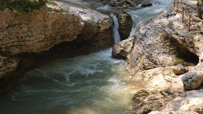 A fast mountain river with a waterfall and rapids in the gorge. Beautiful view of the mountain river. Active recreation in the mountains.