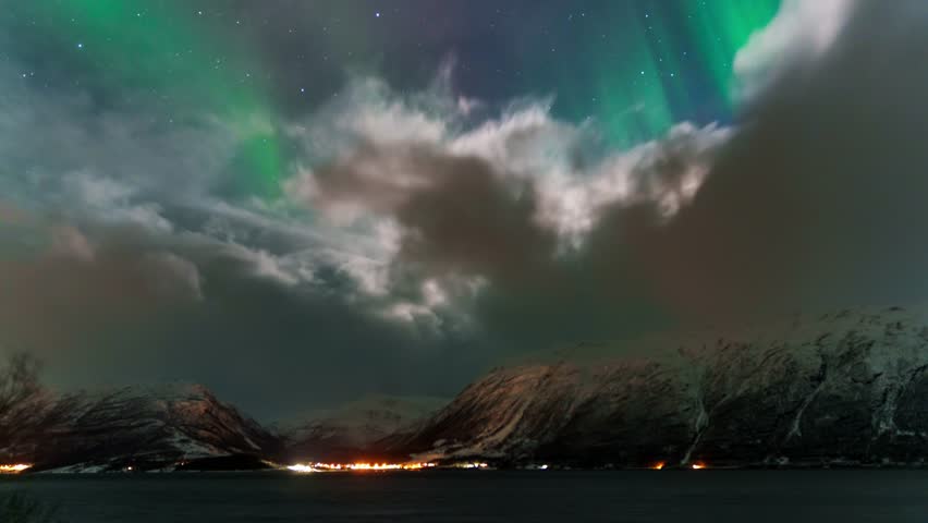 Dancing Northern Lights over a snowy coastal landscape in a mesmerizing timelapse