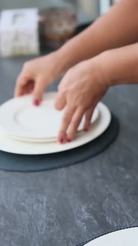 A waiter putting on the white plate on a table with a white table cloth