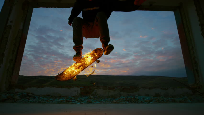 Skateboarder performing flaming tricks at sunset.