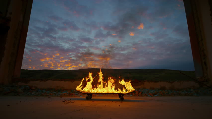 A skateboard engulfed in flames set against a dramatic sunset.