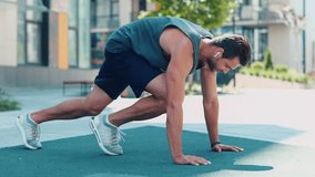 Young man exercising outside. Video process of guy doing mountain climber exercise. Running fast in horizontal position on the same place. Training near urban view. - Powered by Shutterstock - Get 15% off with code: PIKWIZARD15