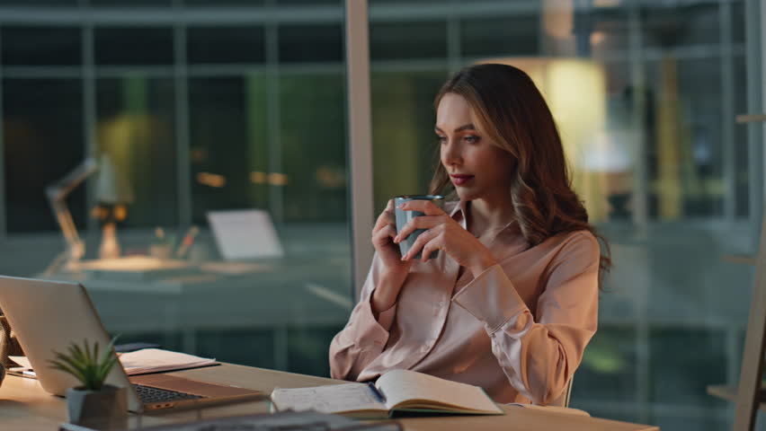 Entrepreneur relaxing evening office with coffee. Thoughtful professional rest reflecting with mug in hand. Peaceful successful executive dreaming at night workplace. Woman in contemplative mood.