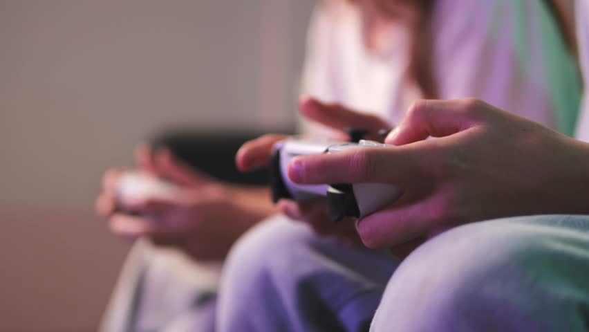 Gaming friends competing intensely, holding controllers while focusing intently on shared digital entertainment experience.People playing console controller, games challenge and entertainment