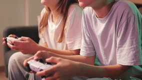 Two young teenagers, boy and girl,sitting on couch, intensely focused on play video game using console controllers, their hands moving quickly and skillfully - Powered by Shutterstock - Get 15% off with code: PIKWIZARD15