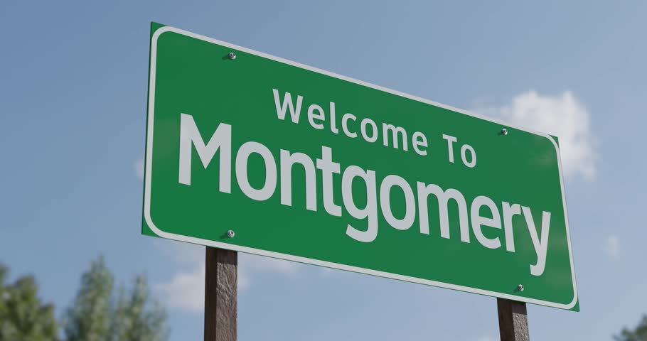 Driving By A Welcome To Montgomery, Alabama Green Road Sign Against A Blue Sky and Clouds.