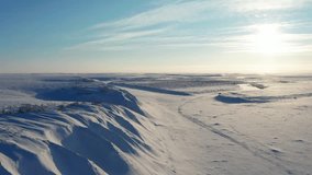 A cinematic drone journey along a wind-sculpted, snow-covered shoreline of a frozen river in the Arctic tundra beyond the Polar Circle. The footage captures the stark beauty of icy landscapes - Powered by Shutterstock - Get 15% off with code: PIKWIZARD15