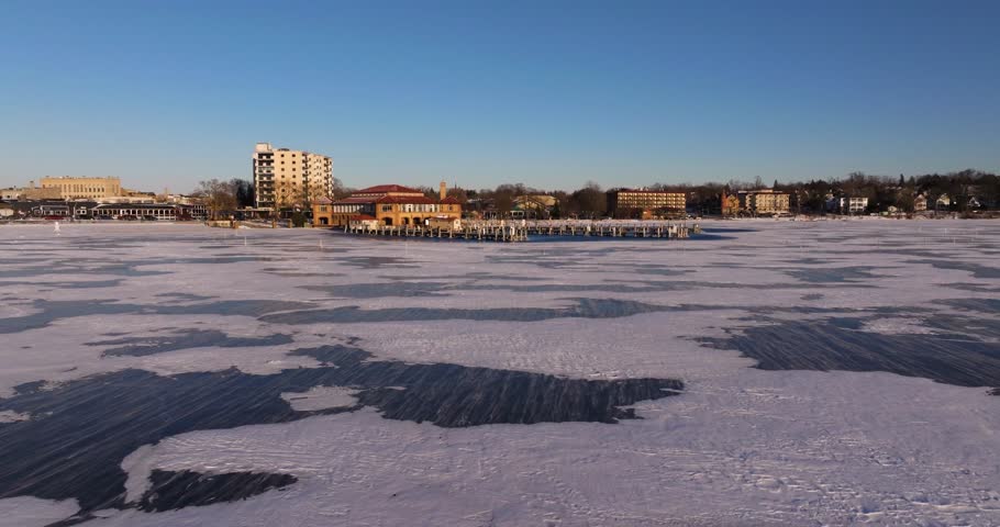 Snow Blowing on Frozen Lake Geneva, Wisconsin in Winter. Establishing Drone Shot