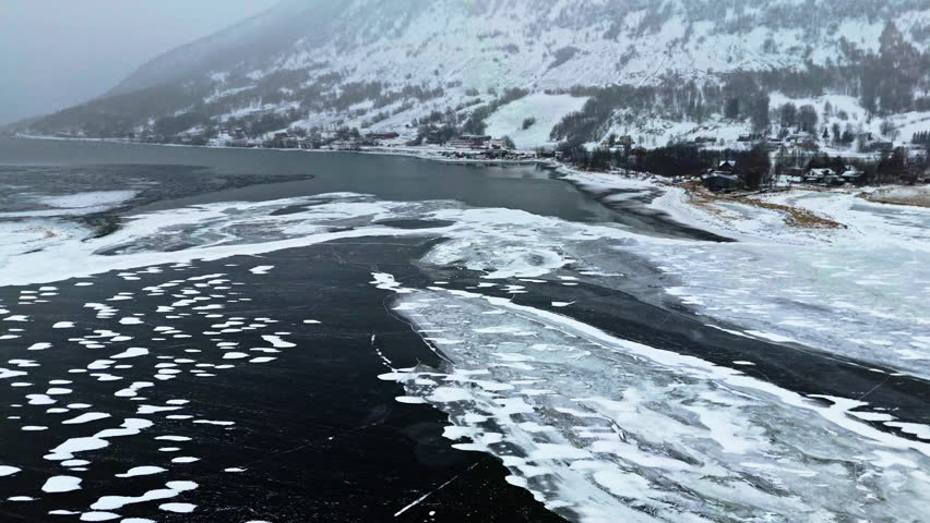 Frozen fjord in Tromsø, Norway, with icy water, snow-covered mountains, and winter vibes
