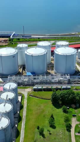 Vertical - Liquefied Natural Gas Tanks At LNG Storage Terminal On Sunny Day. aerial shot