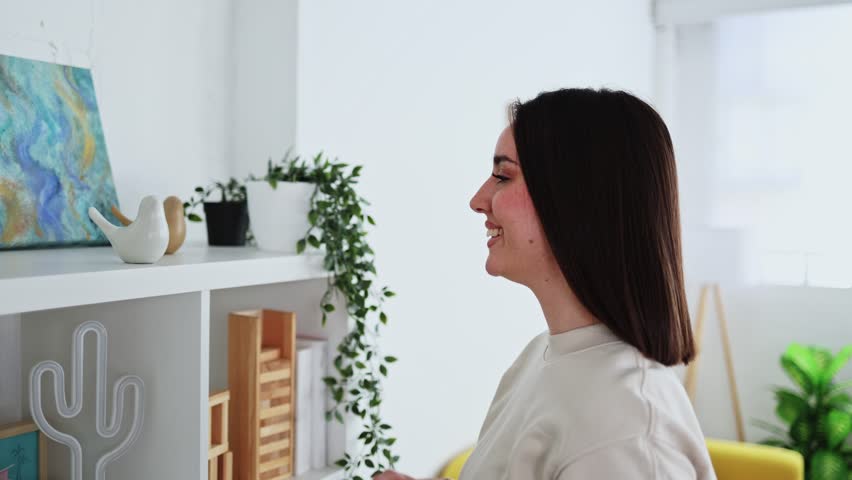 Young woman decorating home with indoor plants and art